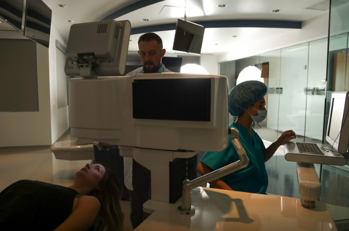 A woman lying on a medical bed with a doctor and nurse nearby.