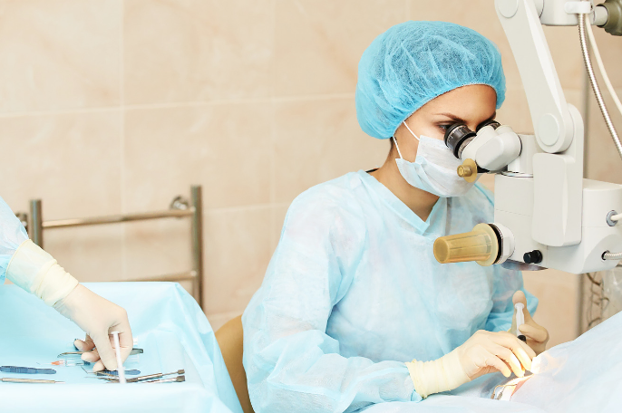 Female surgeon performing eye surgery with a microscope
