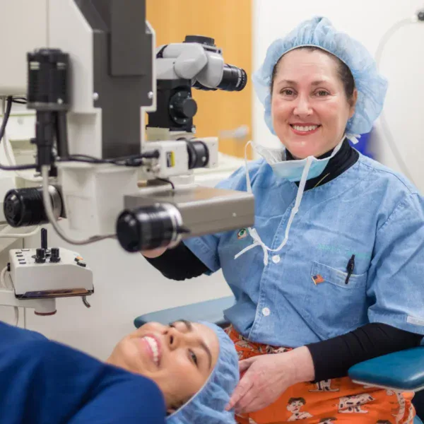 Smiling female surgeon and patient in medical caps and gowns