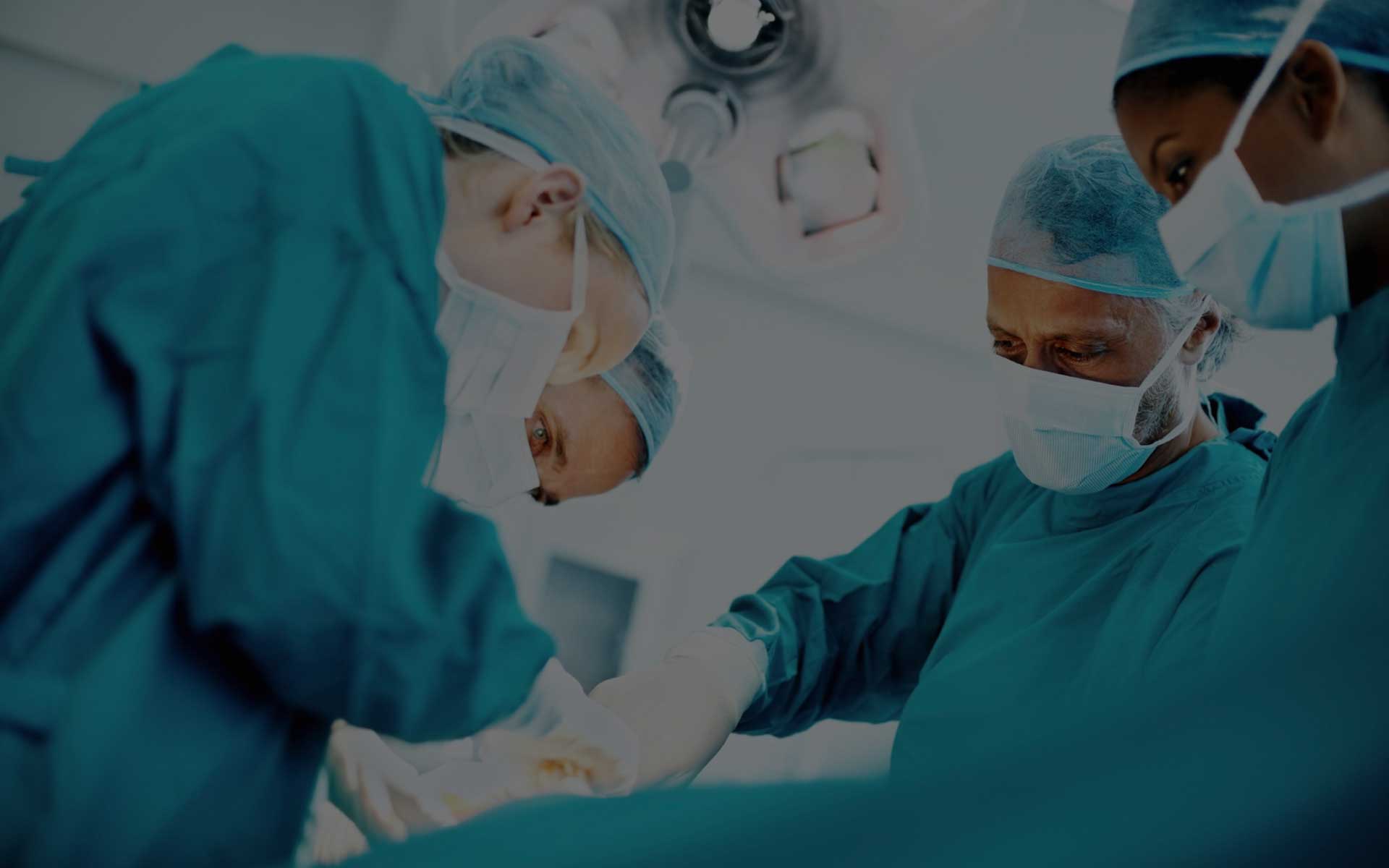 Two surgeons in a hospital operating room with one of them holding the other hand.